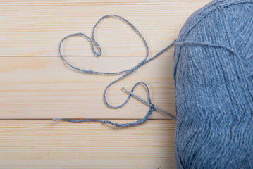 Heart of gray knitting thread. skein of wool and gray yarn for knitting in the wooden background. Heart of knitting yarn, Valentine's Day, concept of love in the hobby. 
