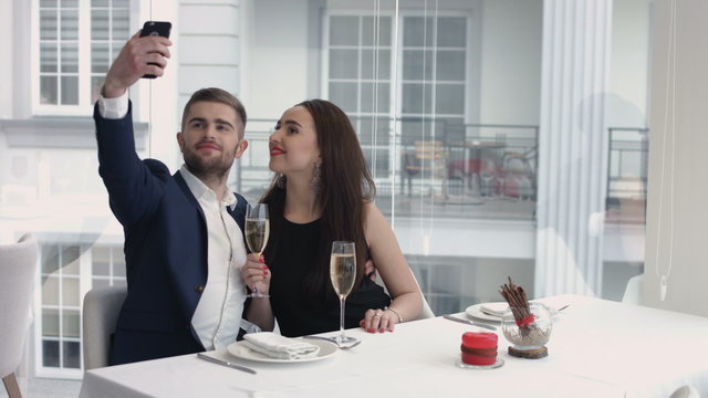 cheerful couple taking a humorous selfie with a smartphone at the restaurant 