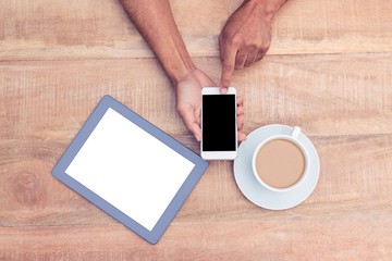 Person using smart phone by coffee and tablet