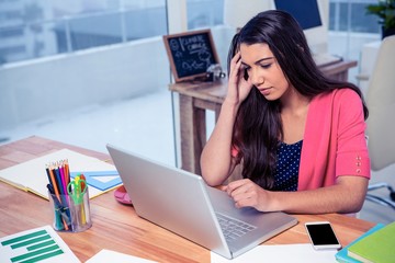 Stressed beautiful businesswoman using laptop