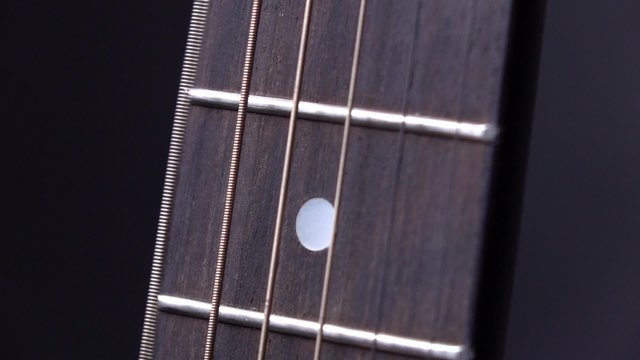 String of acoustic guitar, one move, on black, close up, slow motion