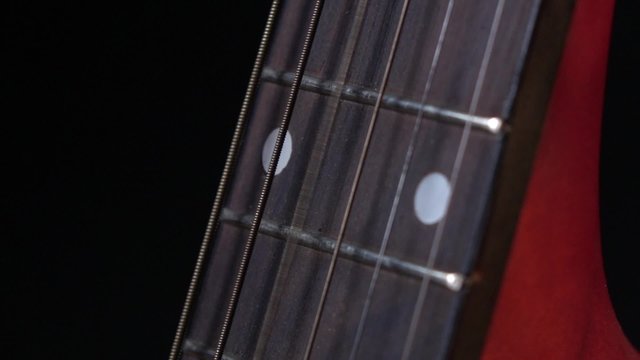 Play strings of acoustic guitar, side view, third string, on black, close up, slow motion