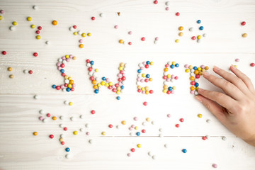 Closeup of woman making word Sweet from colorful candies