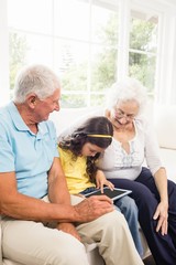 Grandparents using tablet with their granddaughter