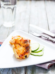 fried mackerel, fish in batter with a fresh cucumber on a white plate