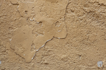 Old ochre painted stucco wall with cracked plaster. Background t