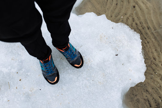 Men's feet in sneakers on the ice near river