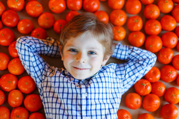 Fototapeta na wymiar Little kid boy with healthy mandarin oranges fruits