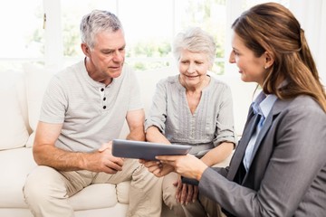 Obraz premium Businesswoman showing tablet to senior couple