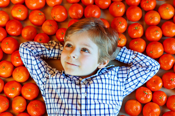 Fototapeta na wymiar Little kid boy with healthy mandarin oranges fruits