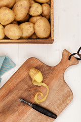 Organic potato and peeling knife on a chopping board