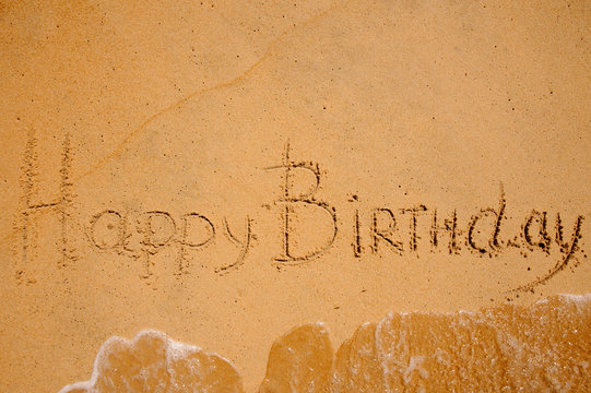 happy birthday sign on the beach washed by wave