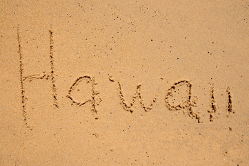 The word Hawaii is written in the sand