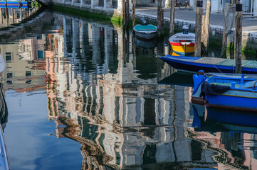 Fototapeta na wymiar View over channel witn boats, houses and reflections in Chioggia