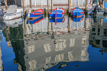 Fototapeta na wymiar View over channel witn boats, houses and reflections in Chioggia