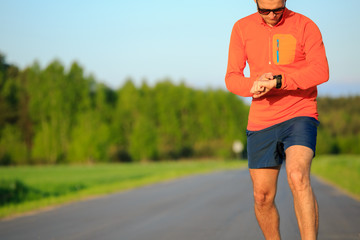 Runner training and checking stopwatch smart watch, cross countr