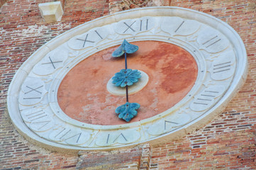 Ancient city clock on a wall of a church in Chioggia
