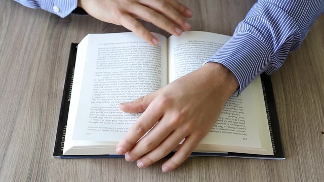 mani che sfogliano le pagine di un libro su un tavolo