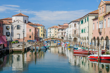 Fototapeta na wymiar View over channel witn boats, houses and reflections in Chioggia