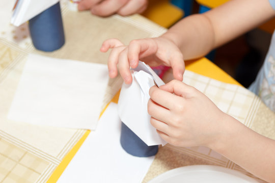 small child hands glue paper crafts at school desk