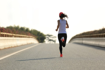 young sports woman runner running on city road