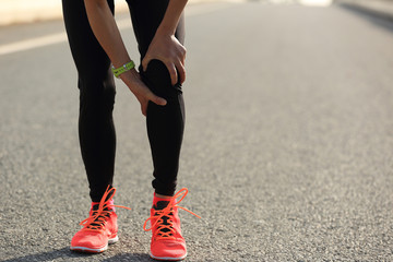 Fototapeta na wymiar woman runner hold her injured leg on road..