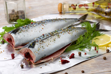 Fresh mackerel in foil with vegetable oil and spices on blurred background.