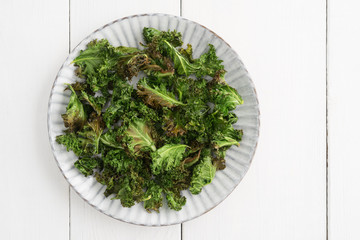 Kale chips with sea salt on a white plate