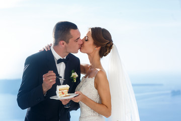 Happy bride and groom eating delicious wedding cake closeup