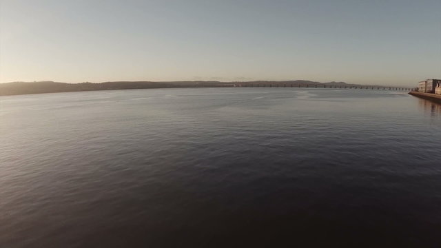 Cinematic aerial shot of the Tay bridge in Dundee during sunrise on a calm morning
