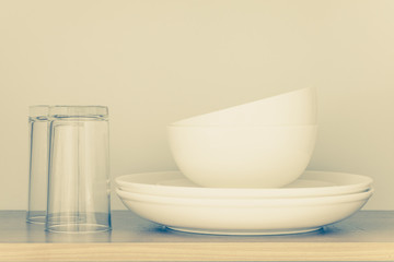 Fototapeta na wymiar White bowl and empty glass in kitchen cabinet