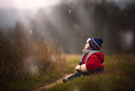 Little Boy Watching Falling Snow. Early Winter Caucasian Child Portrait.