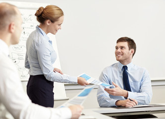 smiling woman giving papers to man in office