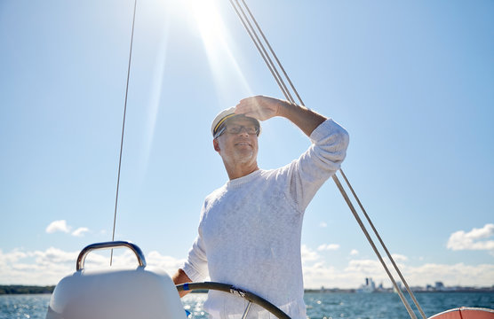 senior man at helm on boat or yacht sailing in sea