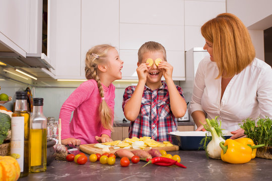 Mother and children having fun in kitchen while cooking together 