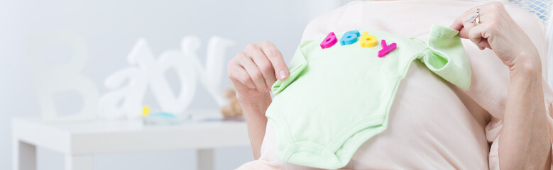 Pregnant woman holding babywear