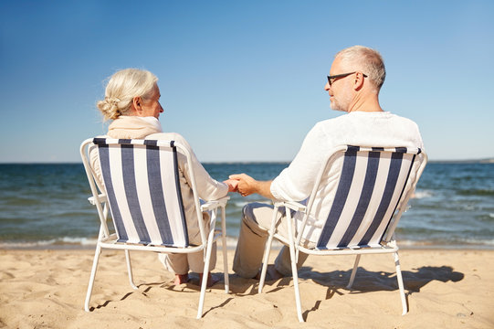 Happy Senior Couple In Chairs On Summer Beach