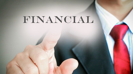 Businessman in suit showing gesture point on text "FINANCIAL" on gray background.