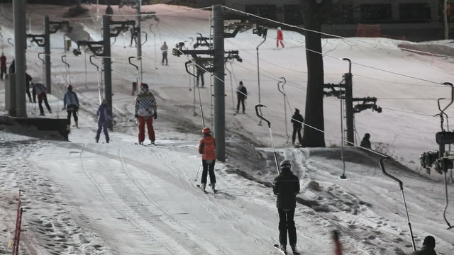 Skiers going uphill on ski lift. Nature and sport background.Skiers and snowboarders at night.night Scene