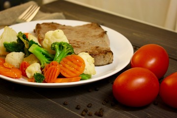 steak with vegetables on a wooden background