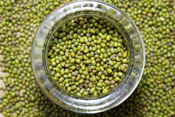 Green mung beans in a glass jar filling the frame making a food texture background.