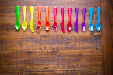 Kids funny eating. Colorful cutlery on wooden table