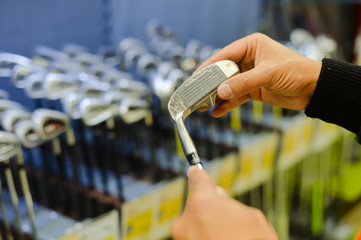 Person holding in hand club at a golf shop. 