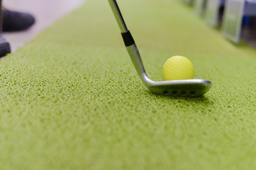 Golf club and ball on green indoor grass background