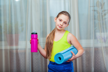 Active Child   holding exercise mat and water bottle in a home 