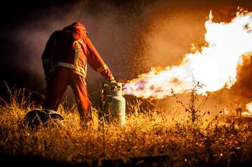 Silhouette of Firemen fighting a raging fire with huge flames of burning timber