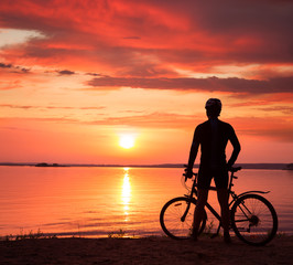 Obraz na płótnie Canvas Man Standing with a Bike at Sunset