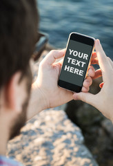 Man with sunglasses using the smartphone near the sea