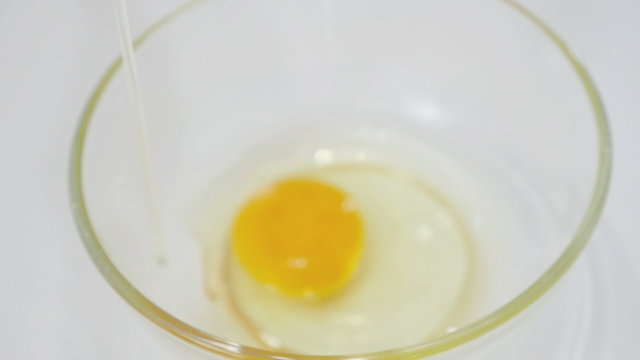 Woman pooring cracked egg in the kitchen