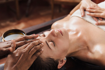 Ayurvedic face massage with oil on the wooden table - obrazy, fototapety, plakaty